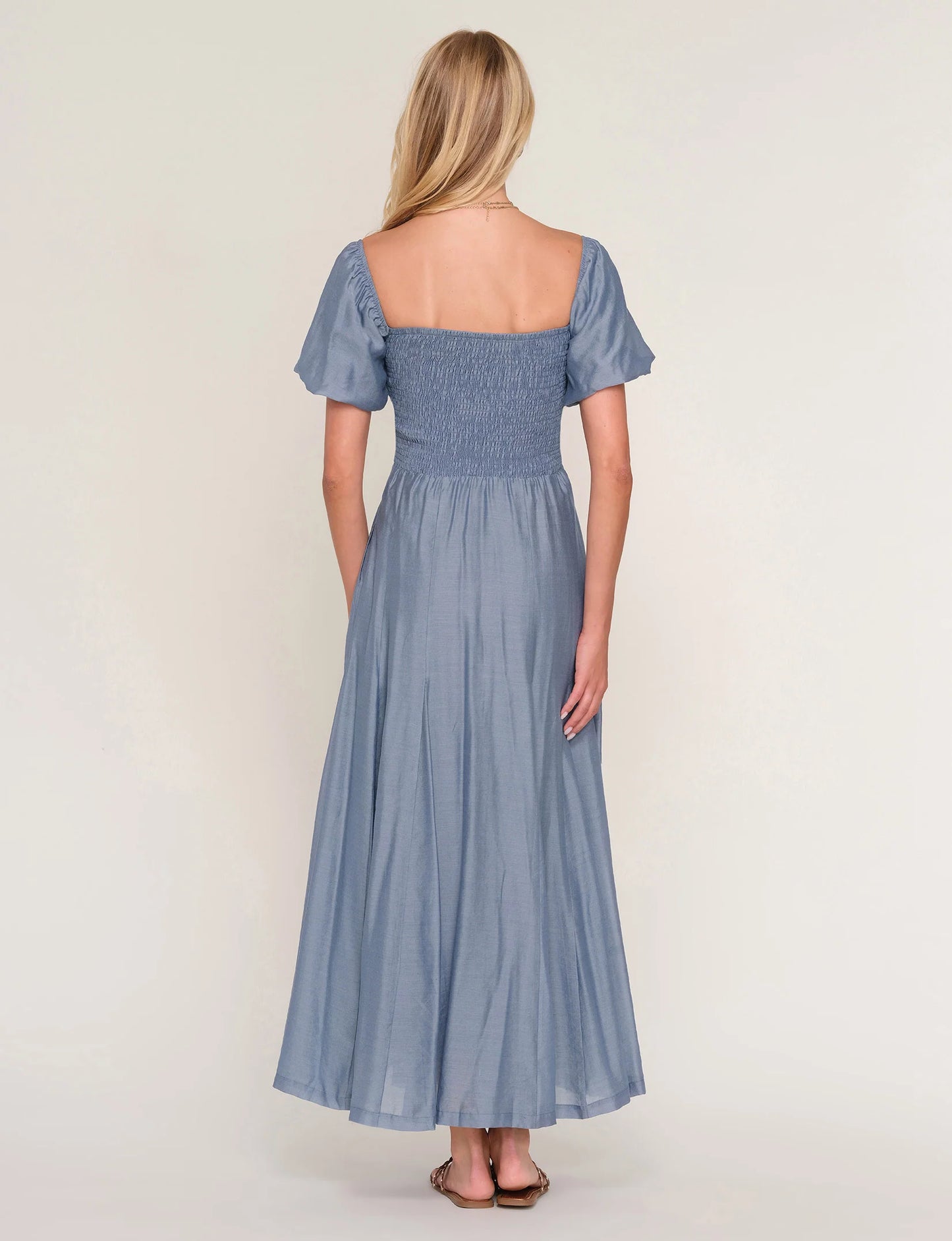 Woman wearing a blue dress with short sleeves on a white background