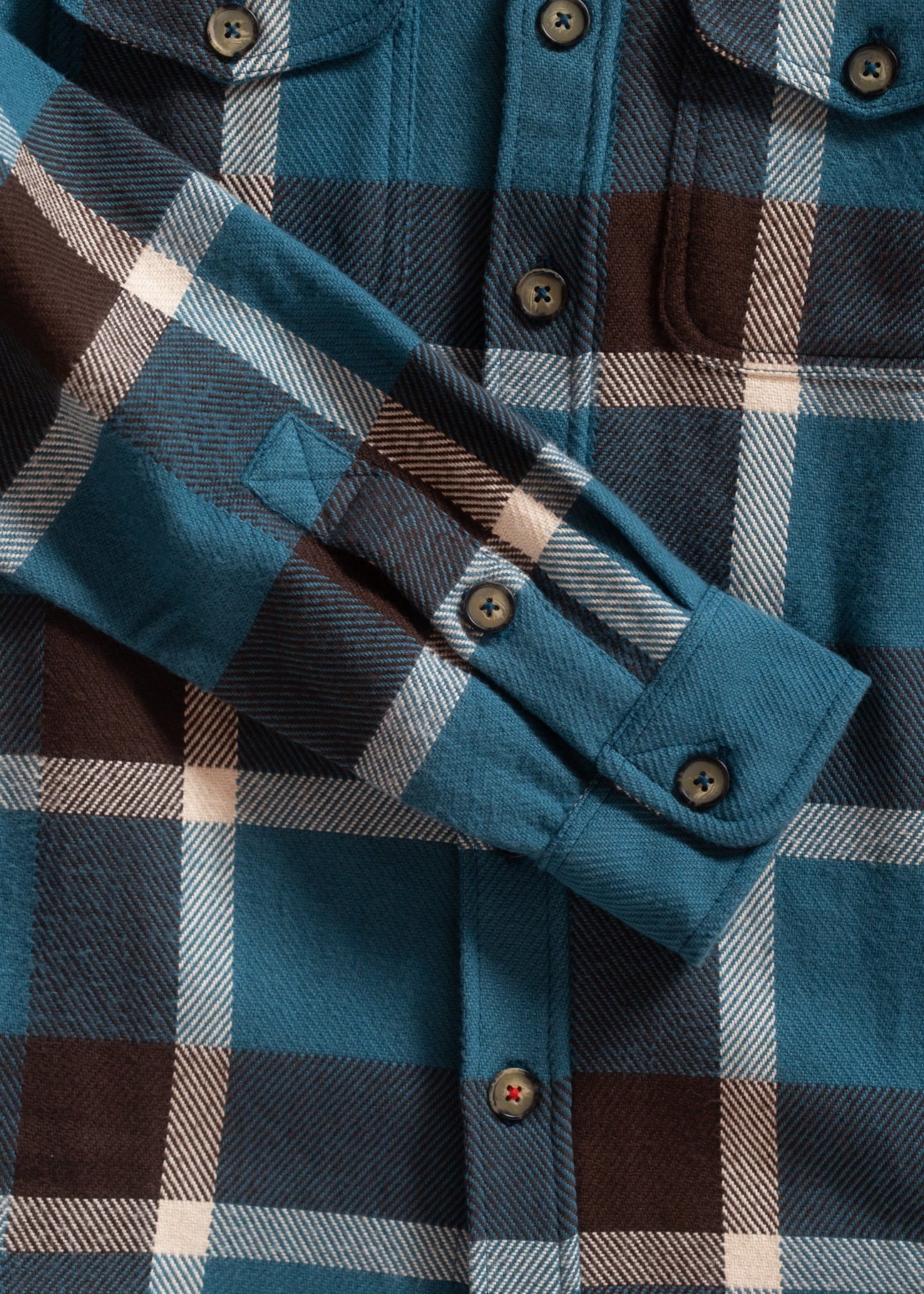 Close-up of a plaid shirt with blue, brown, and beige colors.