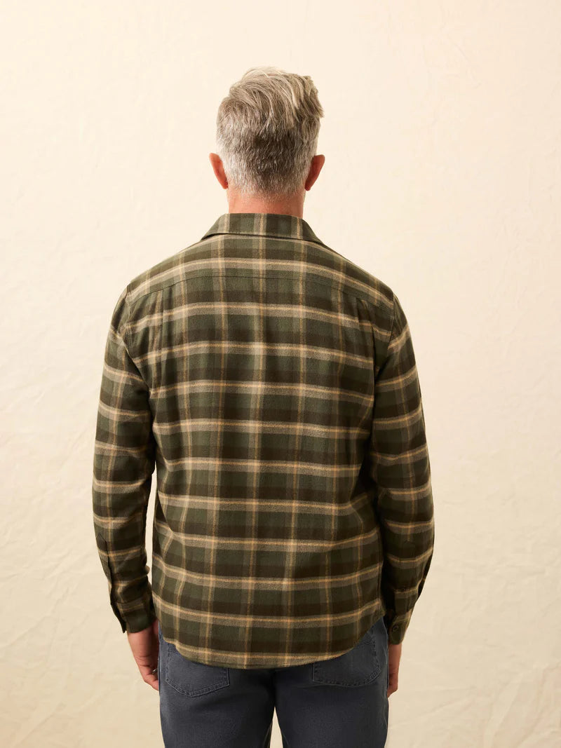 Man wearing a green plaid shirt against a beige background