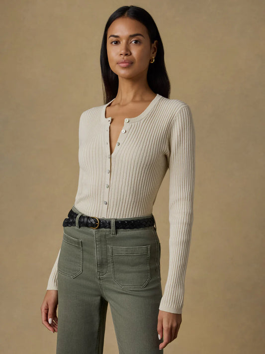 Woman wearing a cream ribbed cardigan and green pants against a beige background