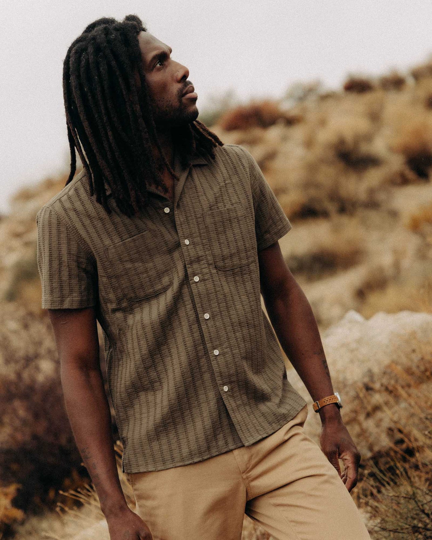 man wearing taylor stitch brand short sleeved shirt the conrad in olive color out in nature