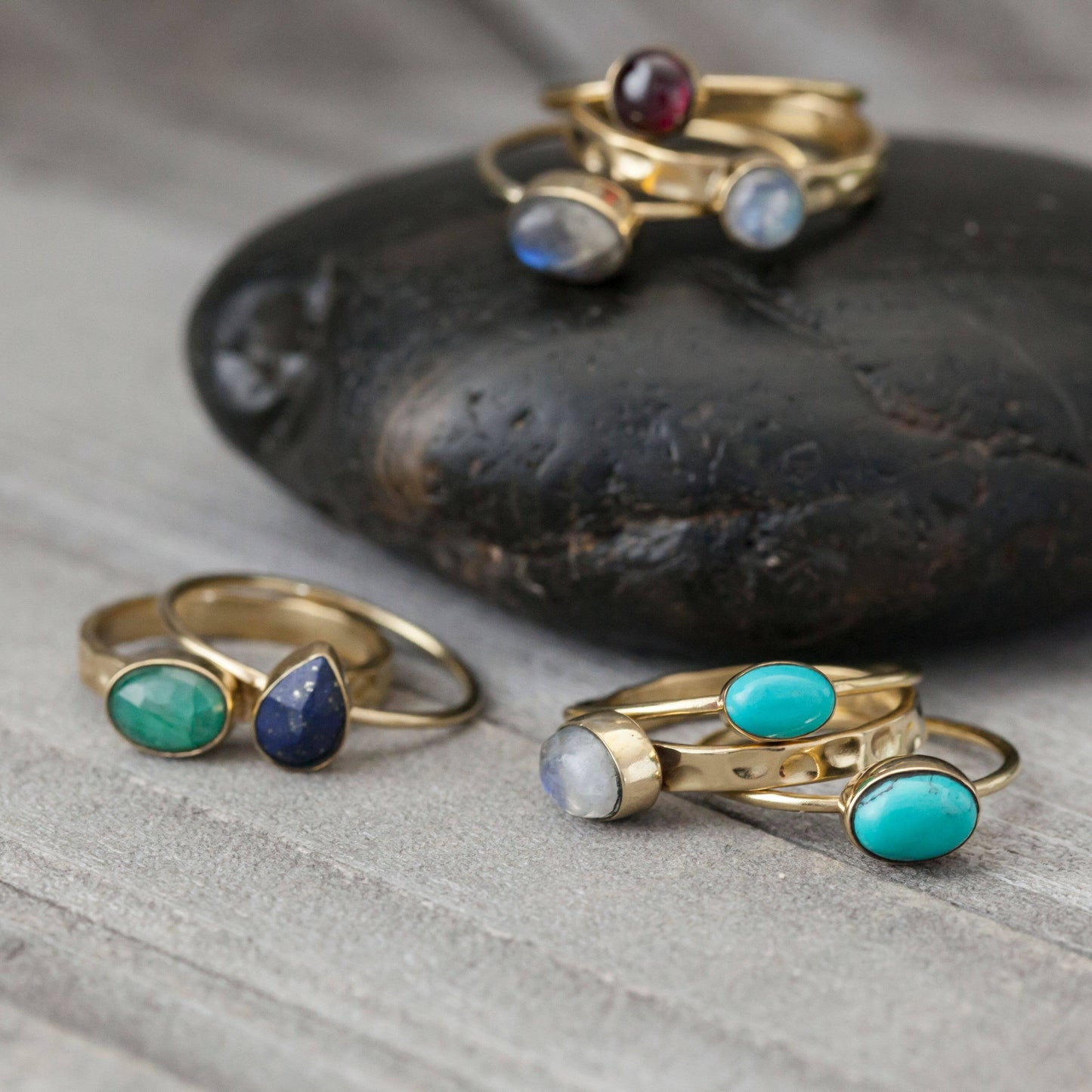 Gold rings with gemstones on a stone surface