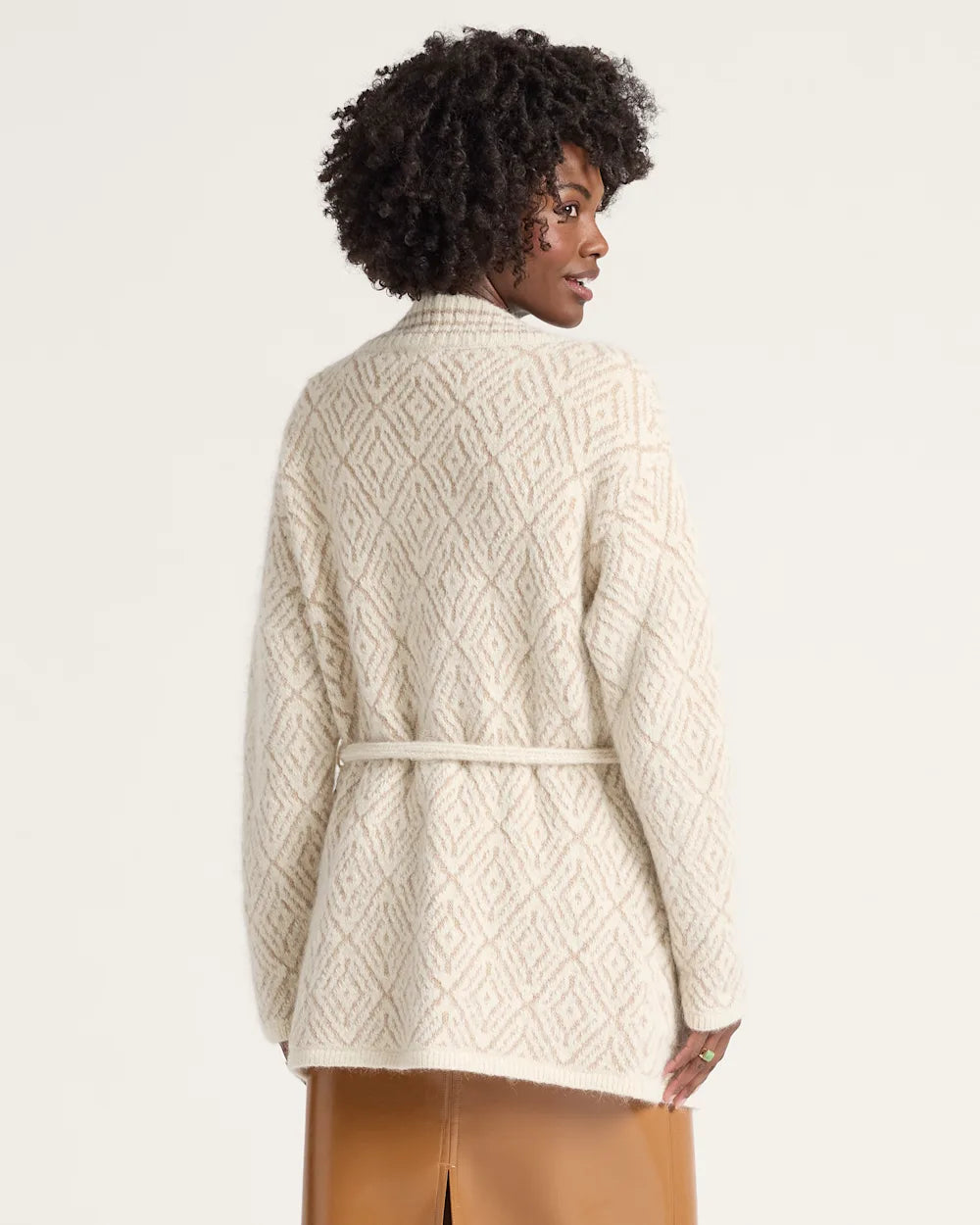 Person wearing a cream-colored cable knit cardigan on a white background