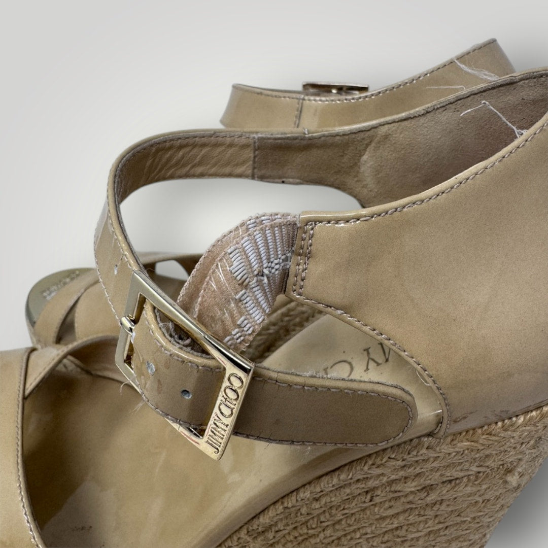 Pair of beige wedge sandals with a strap, showing brand logo on a white background.