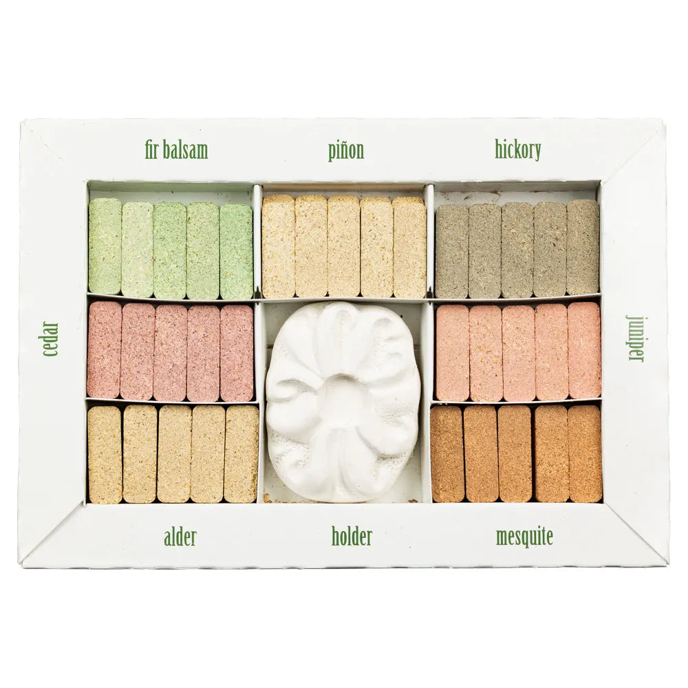 Assorted wood incense samples and an incense holder in a display box with labels on a white background