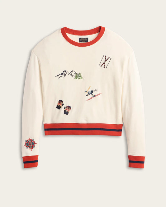 White sweater with red and blue accents featuring skiing-themed embroidery on a light gray background.