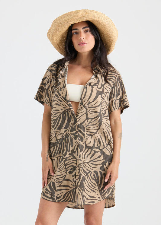 Woman wearing a patterned cover-up and straw hat on a white background