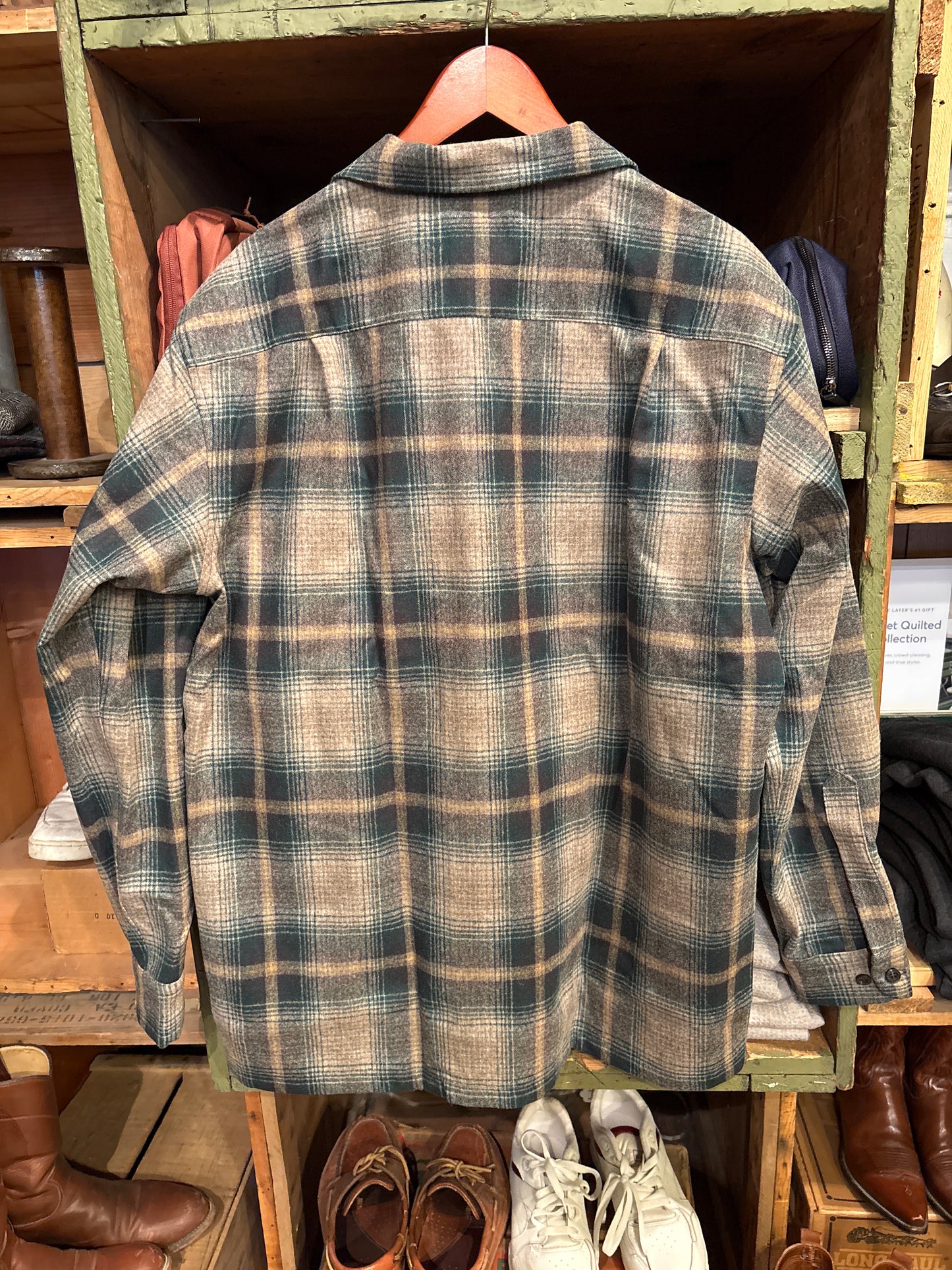 Plaid shirt hanging on a rack with shoes and boxes in the background