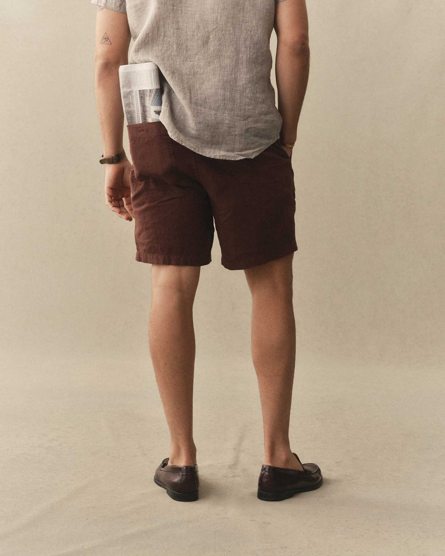 Person wearing brown shorts and a light gray shirt on a beige background