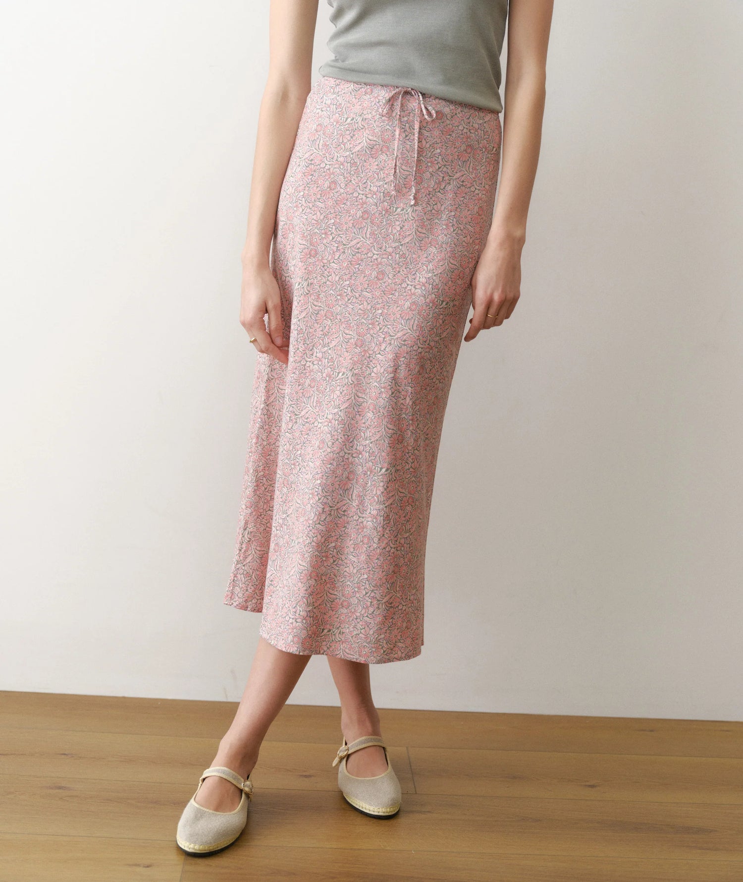 Person wearing a pink floral skirt on a plain background