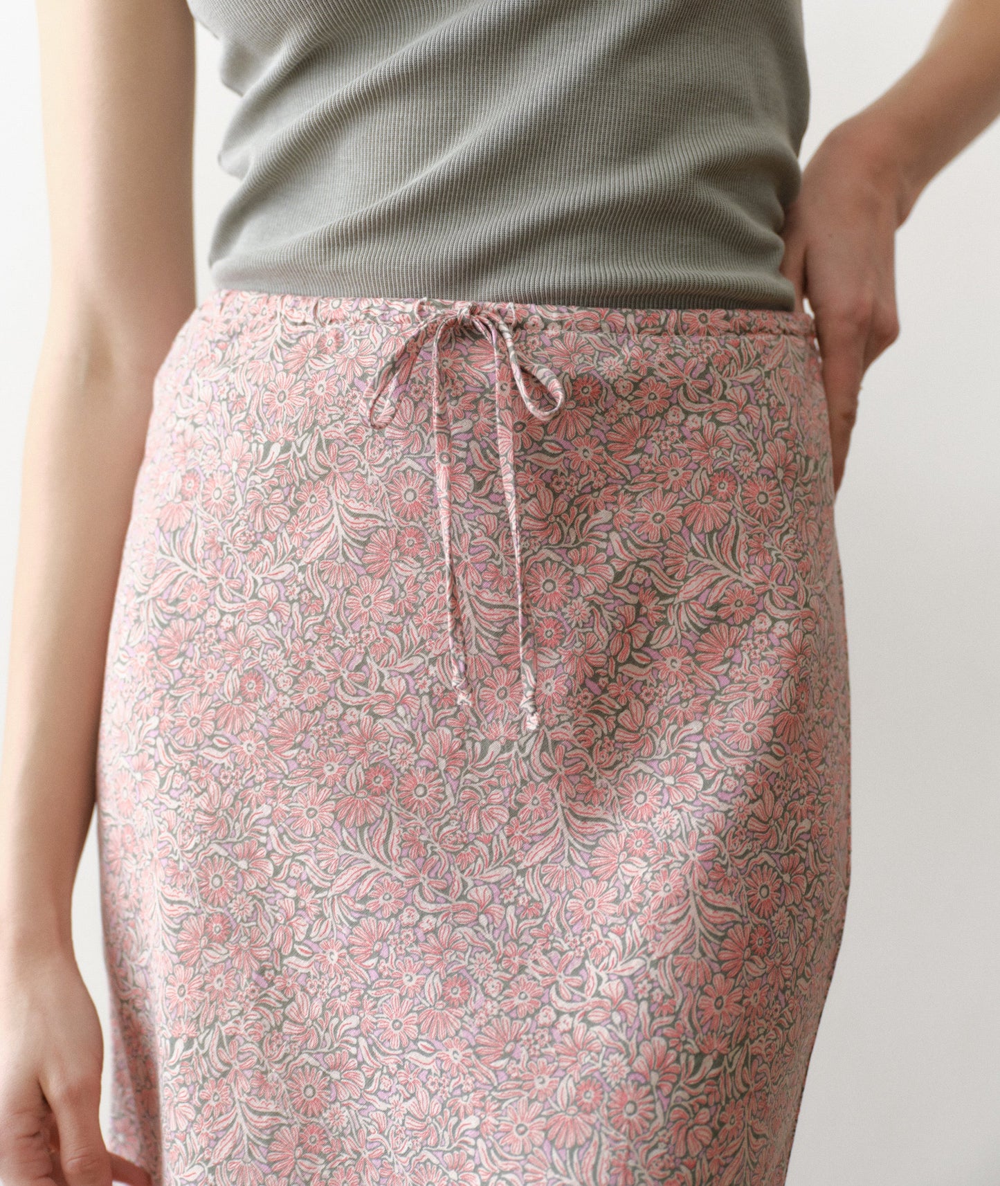 Person wearing a pink floral skirt with a plain background
