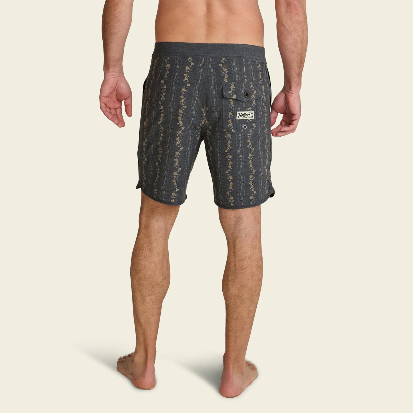 Man wearing dark patterned shorts on a beige background
