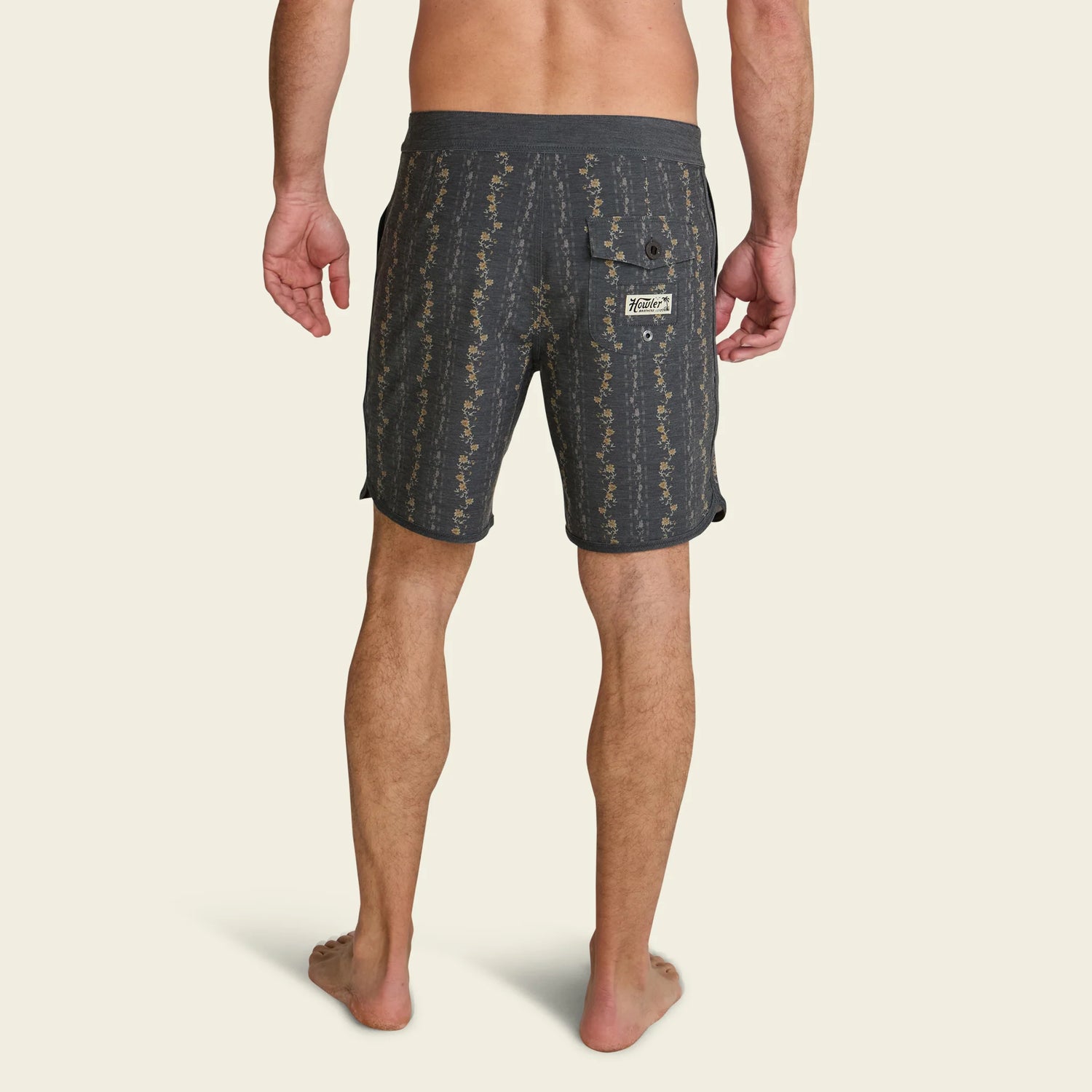 Man wearing dark patterned shorts on a beige background