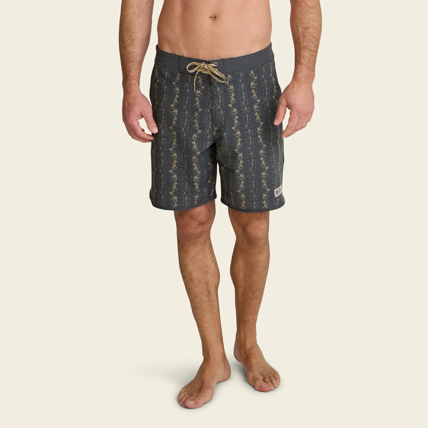 Man wearing dark patterned shorts on a beige background