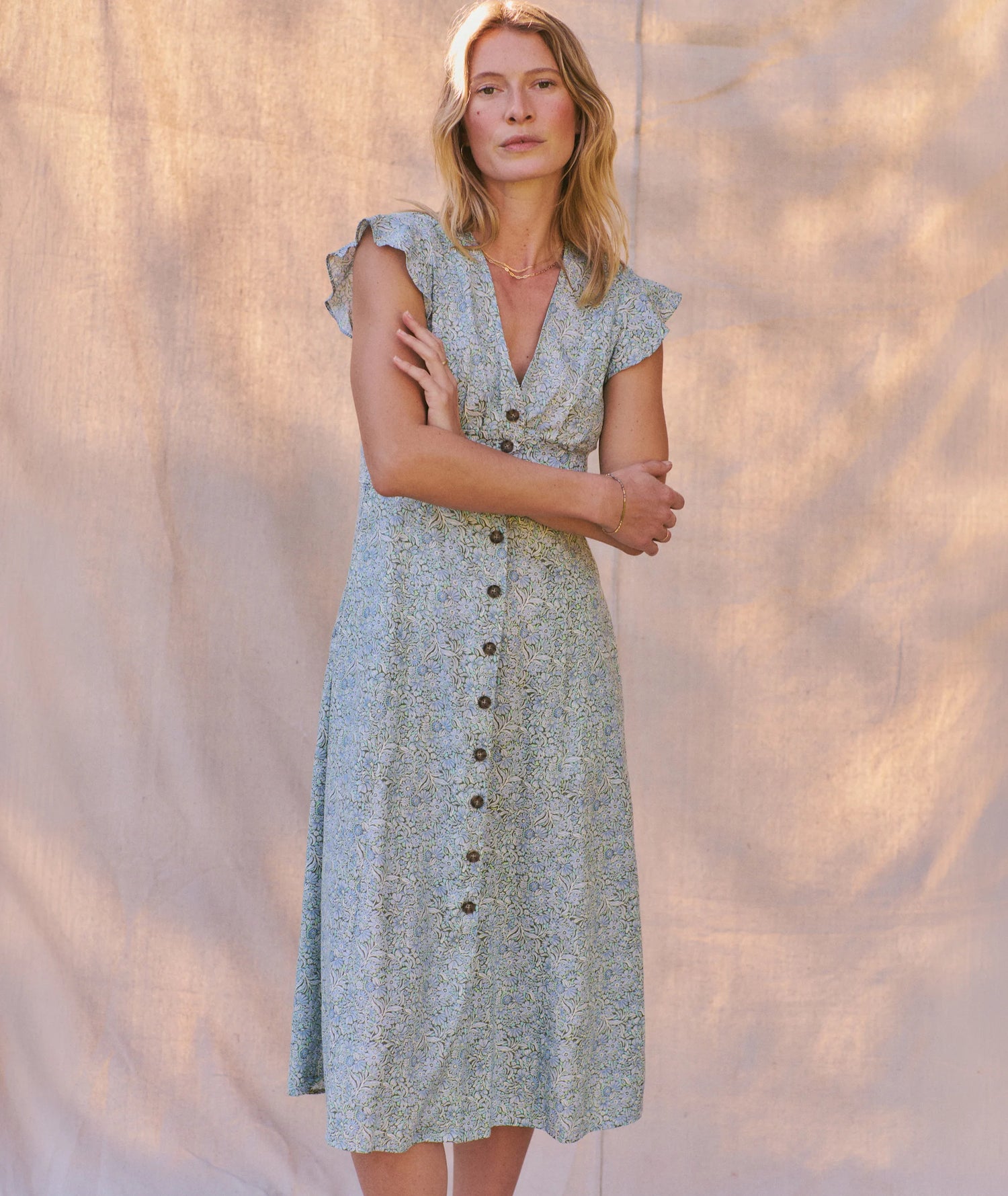 Woman wearing a green floral dress against a textured beige background