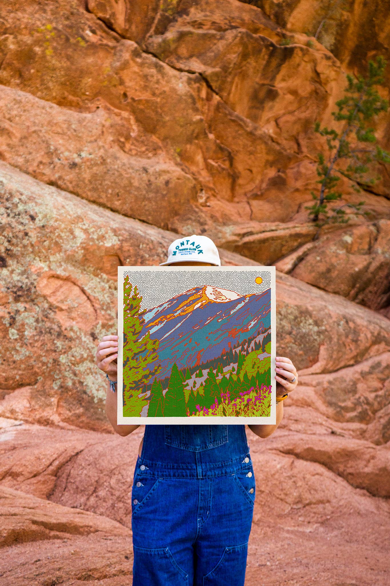 Caroline-Clark-art-print-mstgoods-colorful-landscape-art-3 artist holding print in front of red rocks