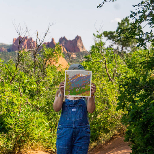Caroline-clark-art artist holding her art in front of her face in Garden of the Gods park