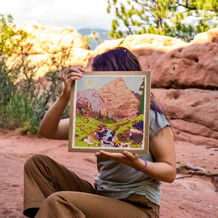 sitting on the ground holding up her art in nature