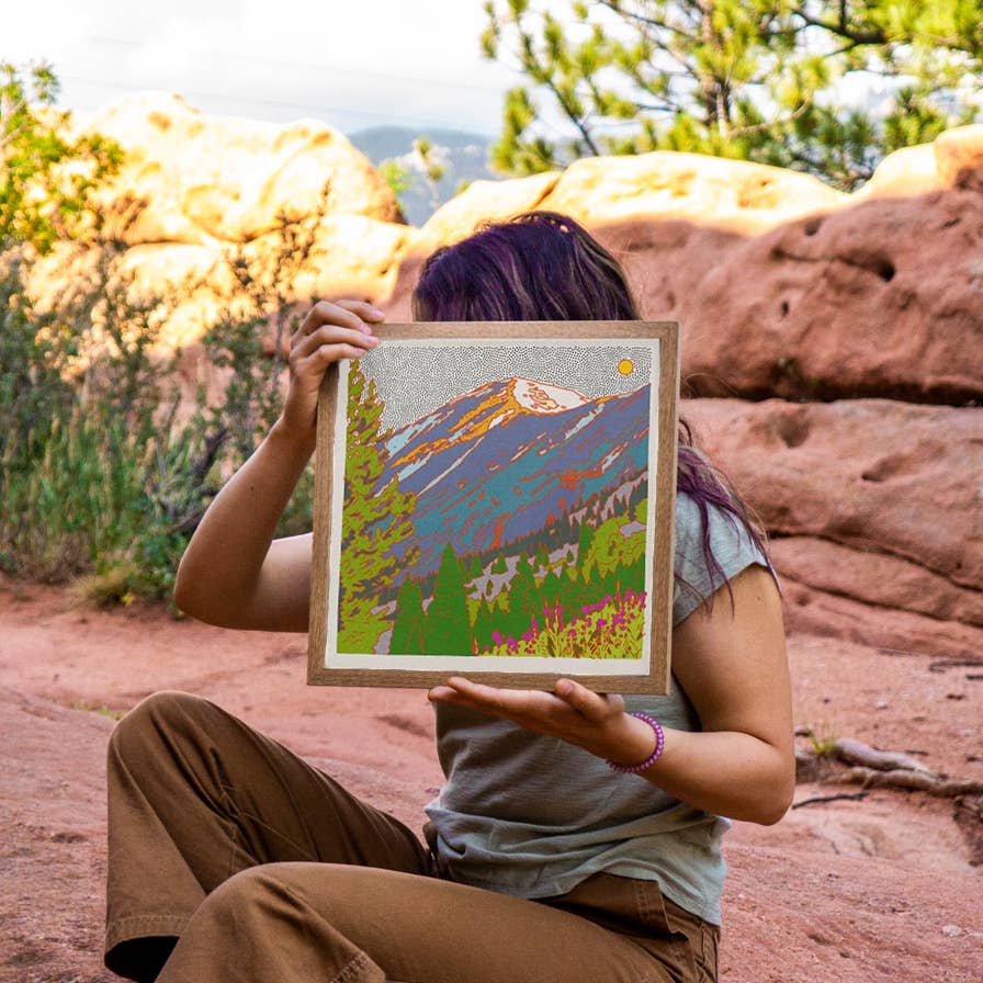 caroline clark colorado landscape artist sitting holding her artwork in nature