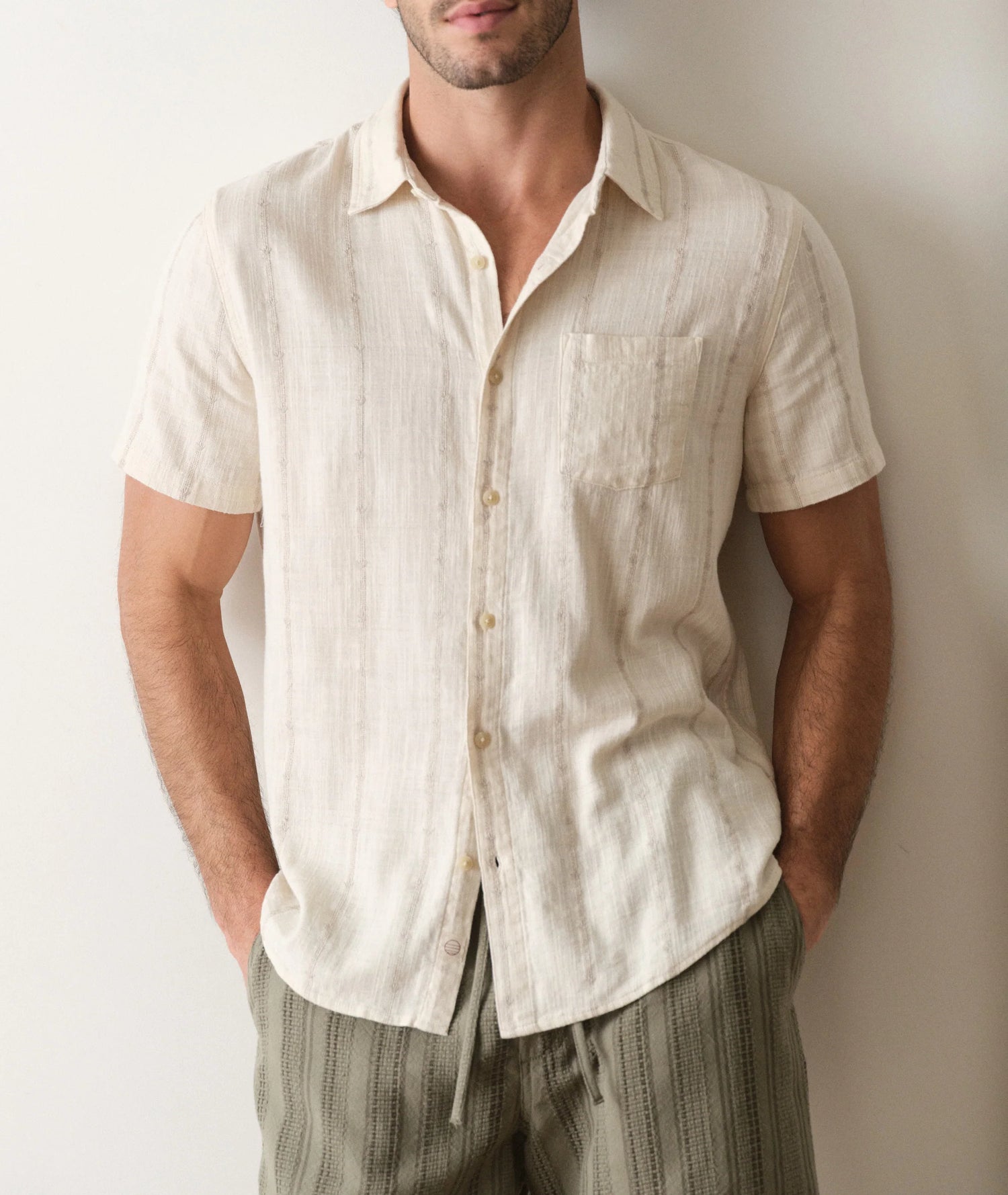 Man wearing a beige short-sleeve shirt against a plain background