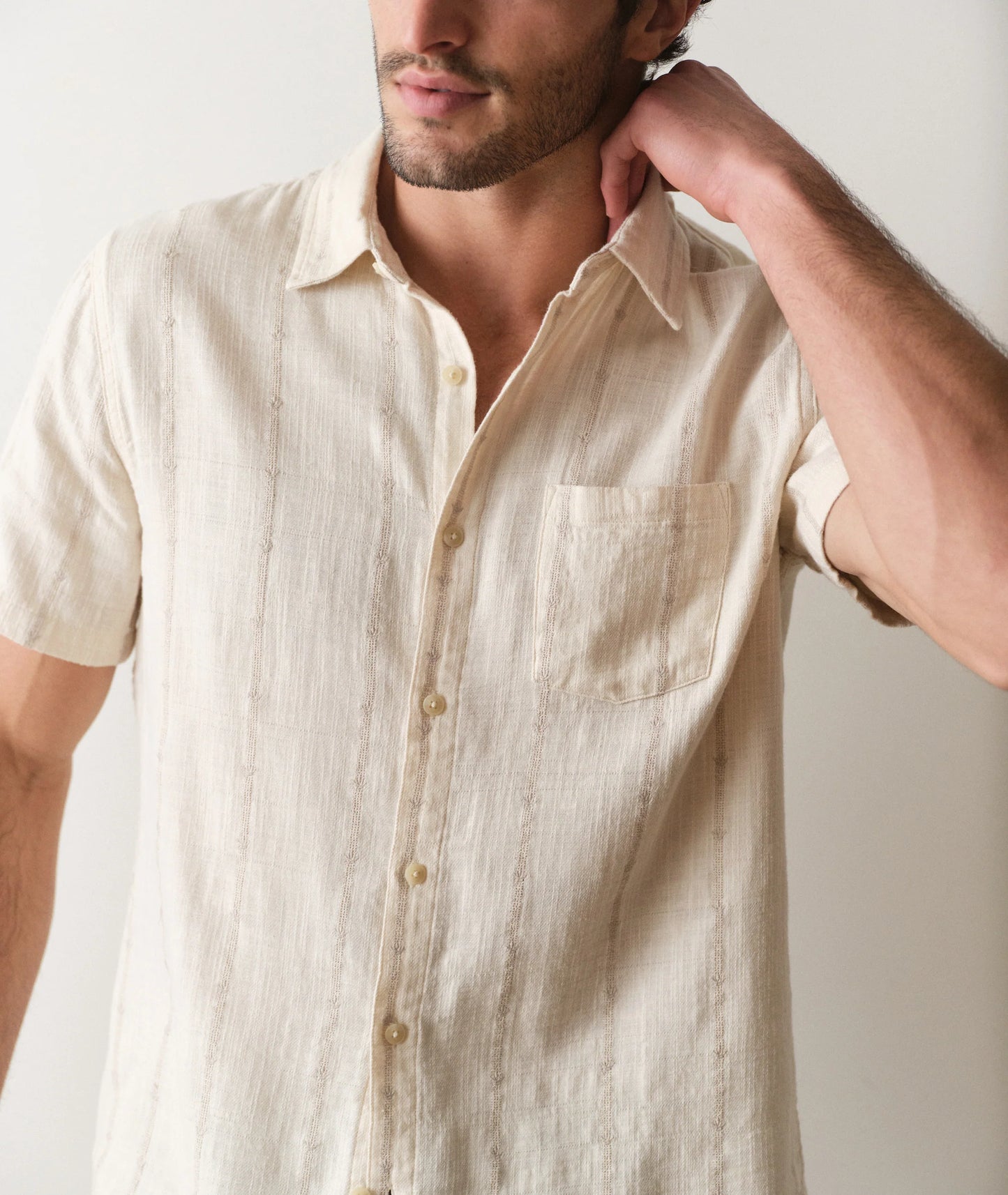Man wearing a beige short-sleeve shirt against a plain background