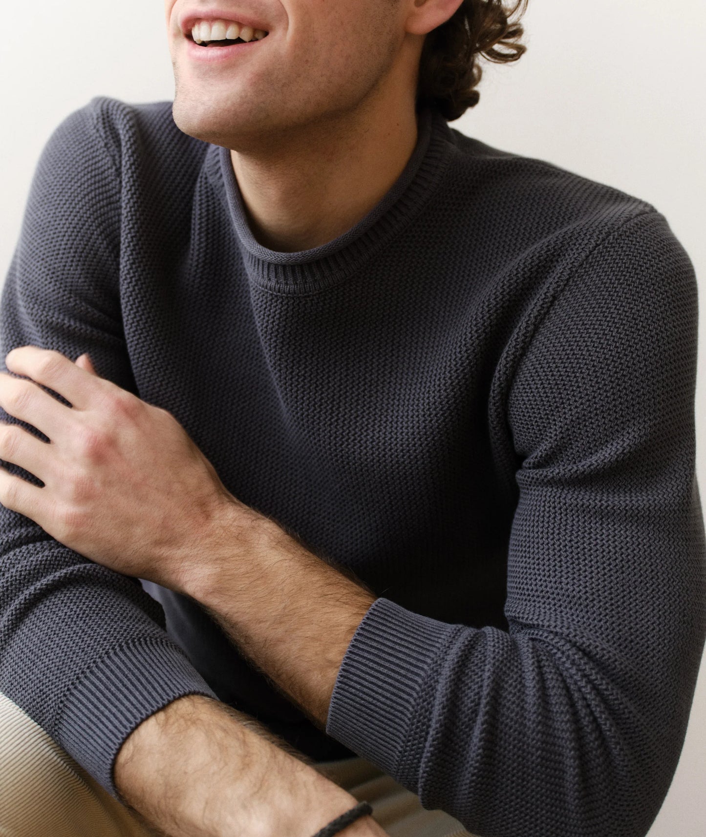 Man wearing a dark gray sweater against a neutral background