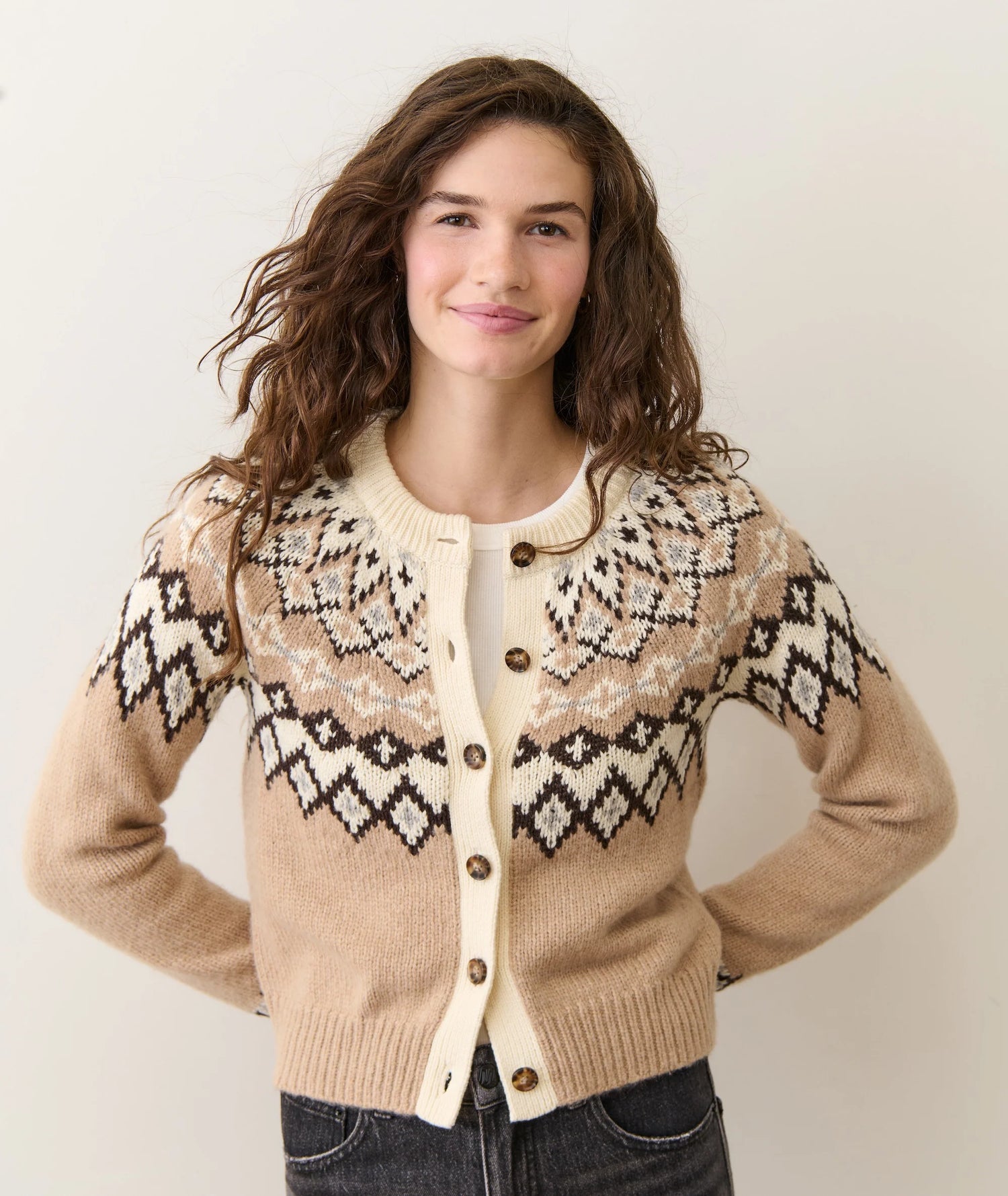 Woman wearing a patterned beige sweater with a plain background