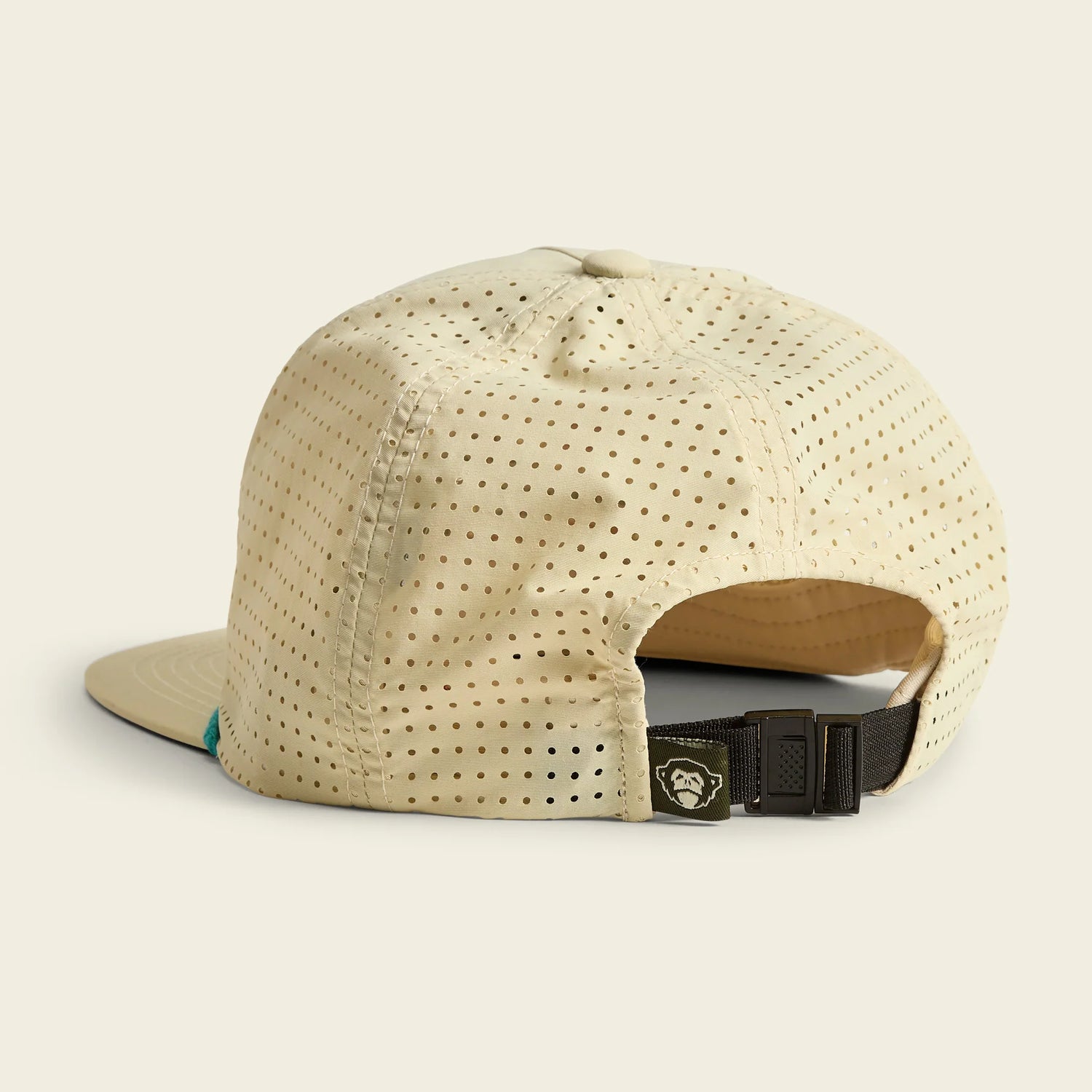 Beige cap with a brown brim and black strap on a light beige background