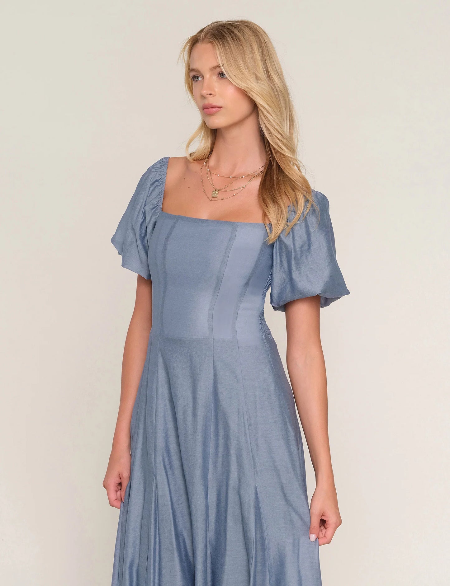 Woman wearing a light blue dress with short sleeves against a plain background