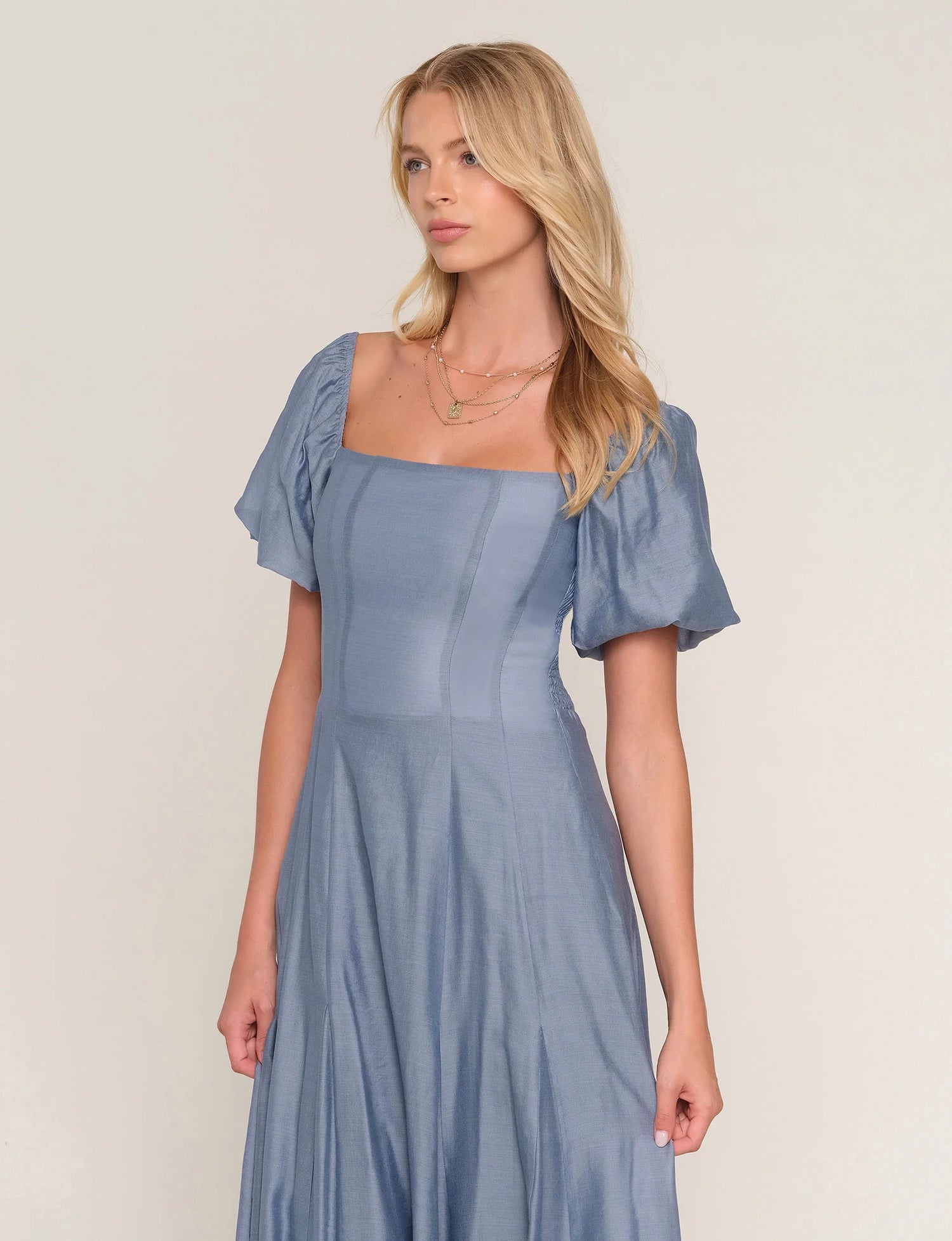 Woman wearing a light blue dress with short sleeves against a plain background