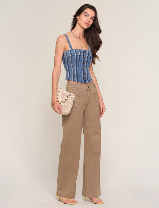 Woman wearing a blue striped top and beige pants against a plain background