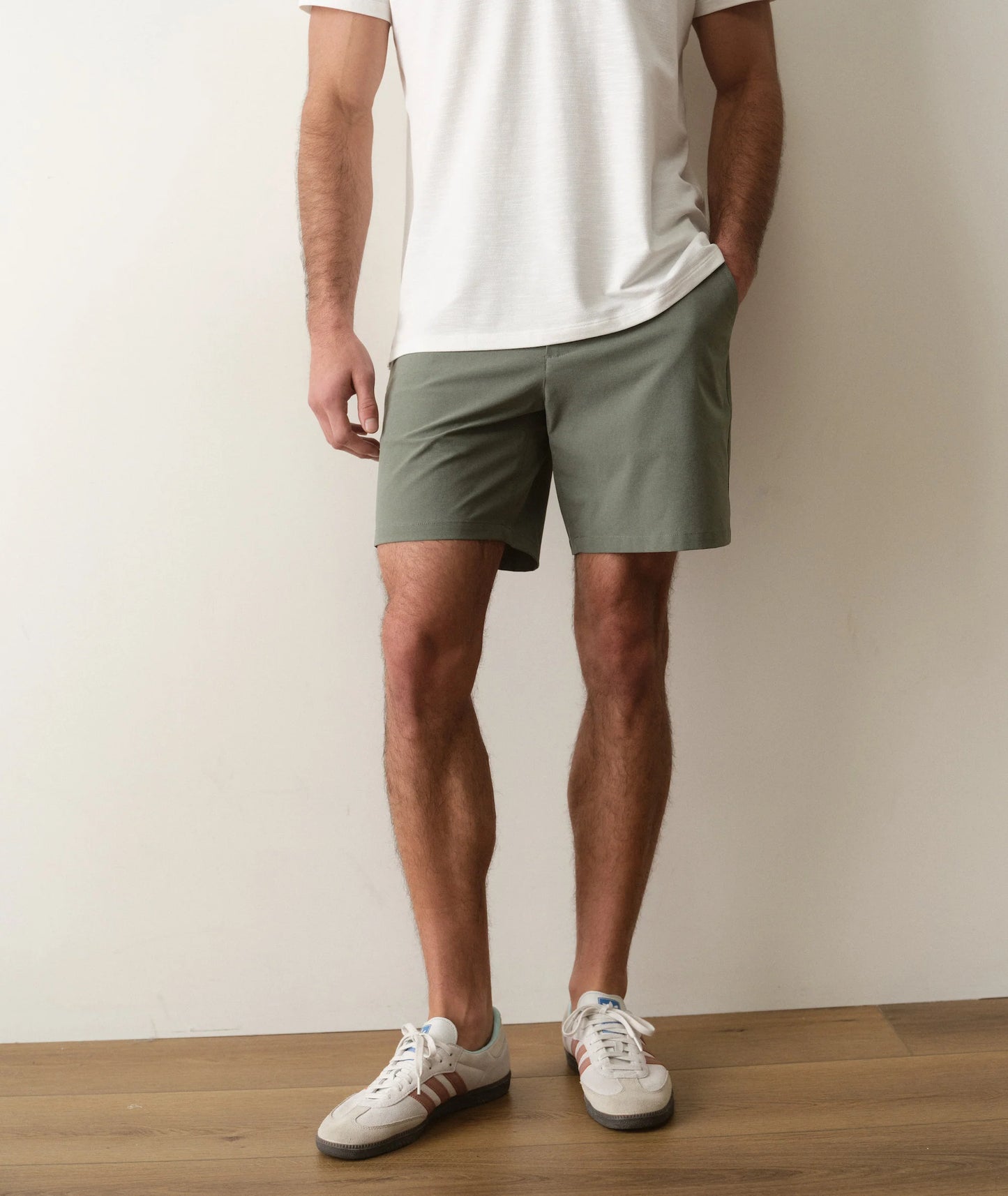 Person wearing green shorts and white sneakers on a plain background