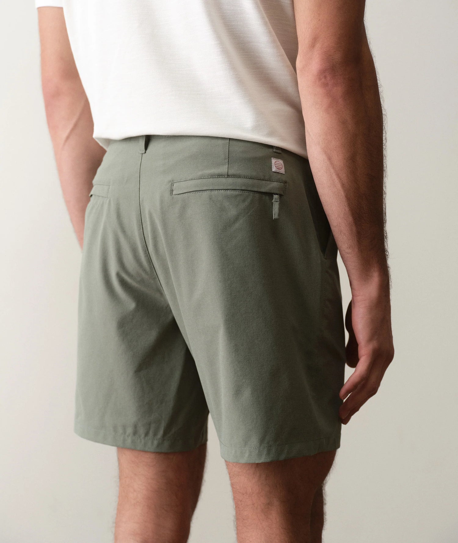 Person wearing green shorts and a white shirt against a neutral background