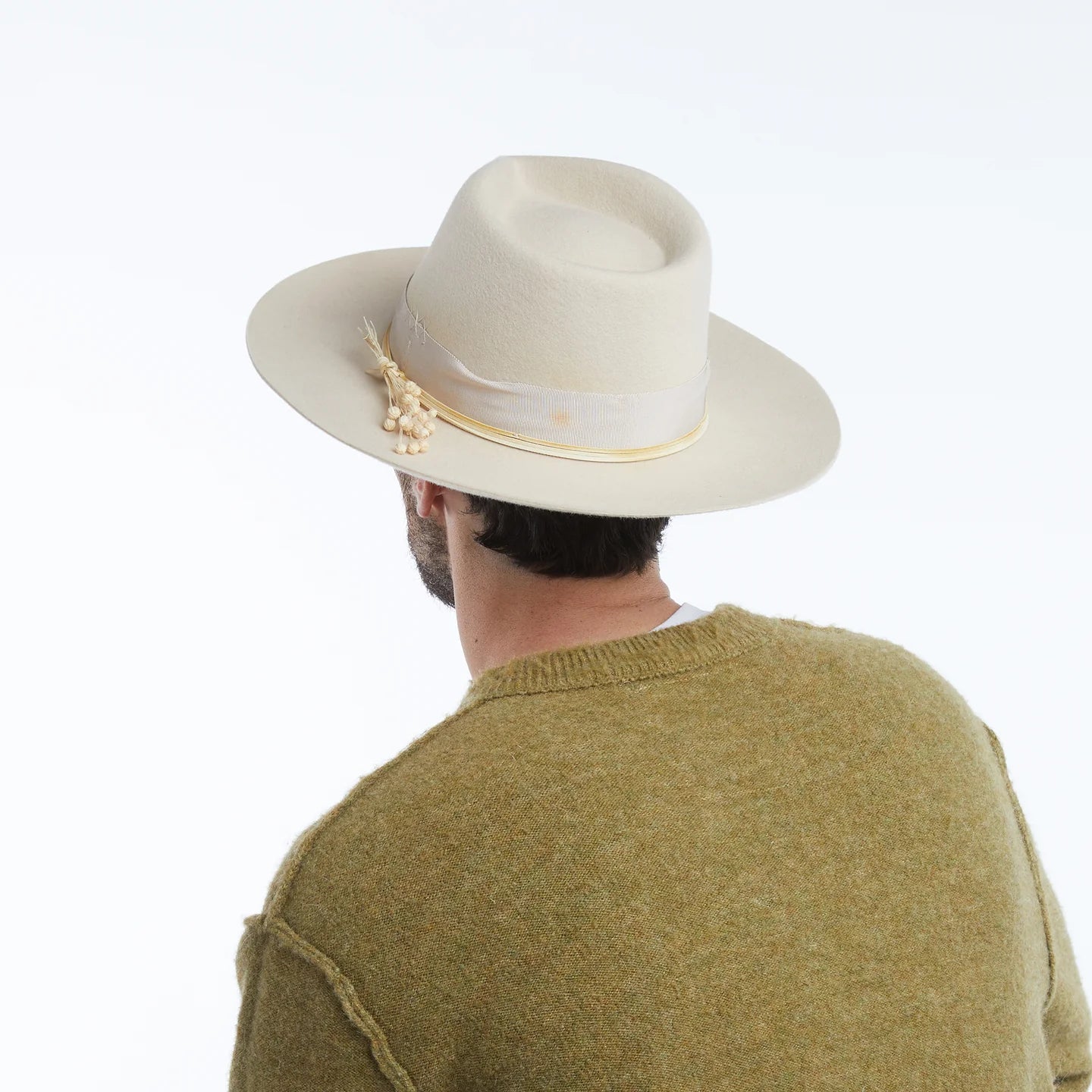 Person wearing a beige hat with decorative elements on a white background