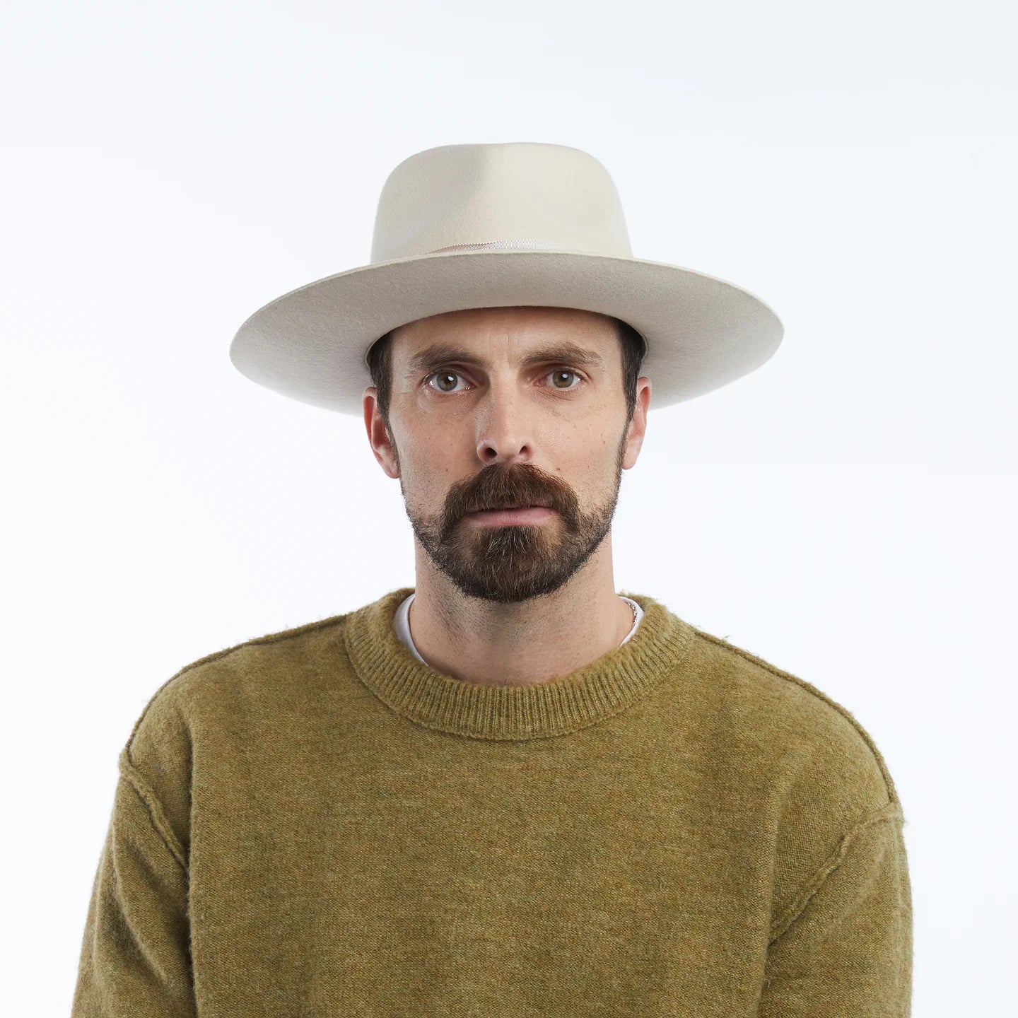 Man wearing a beige hat and green sweater on a white background