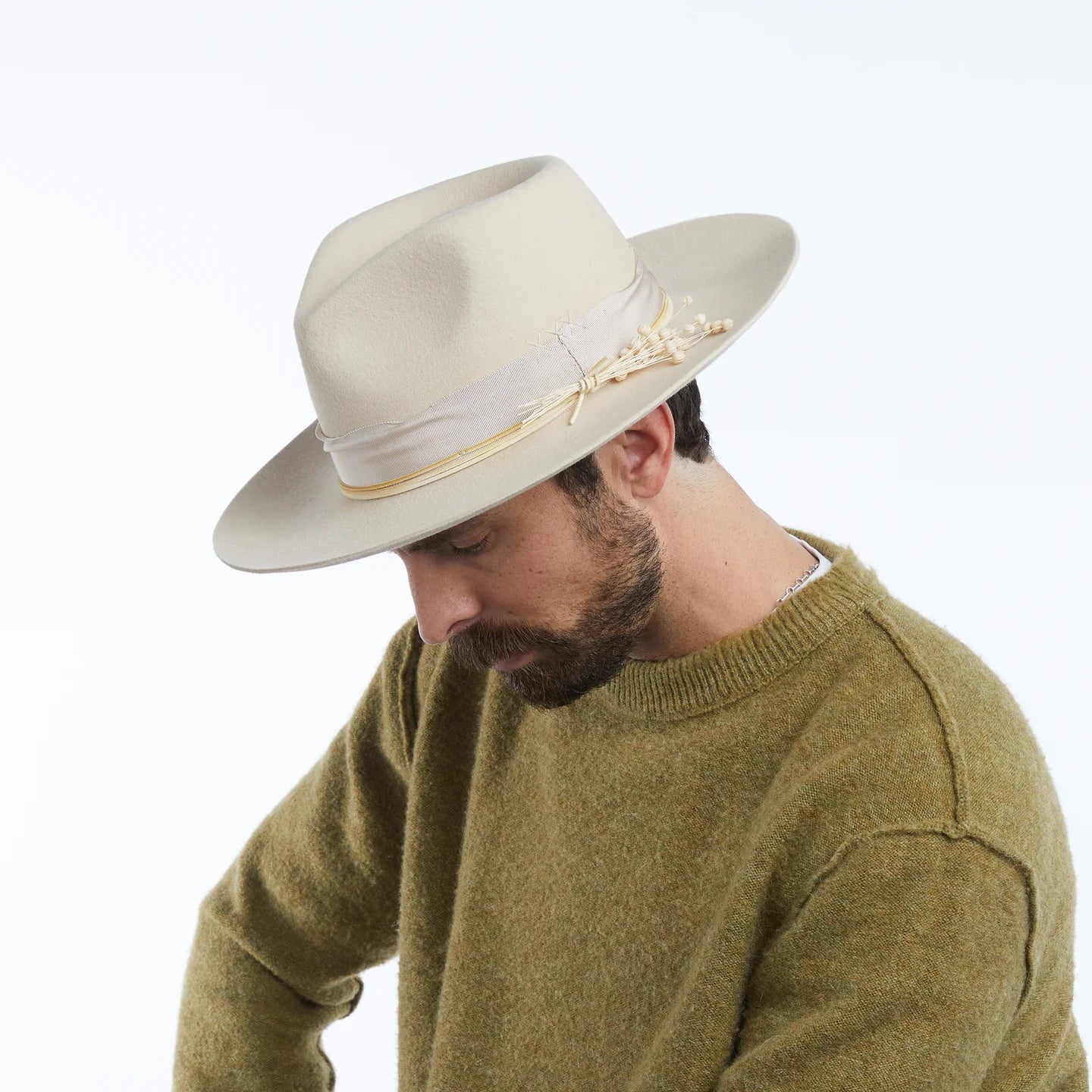 Man wearing a beige fedora with a ribbon on a white background