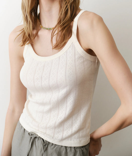 Person wearing a white tank top and gray pants against a plain background