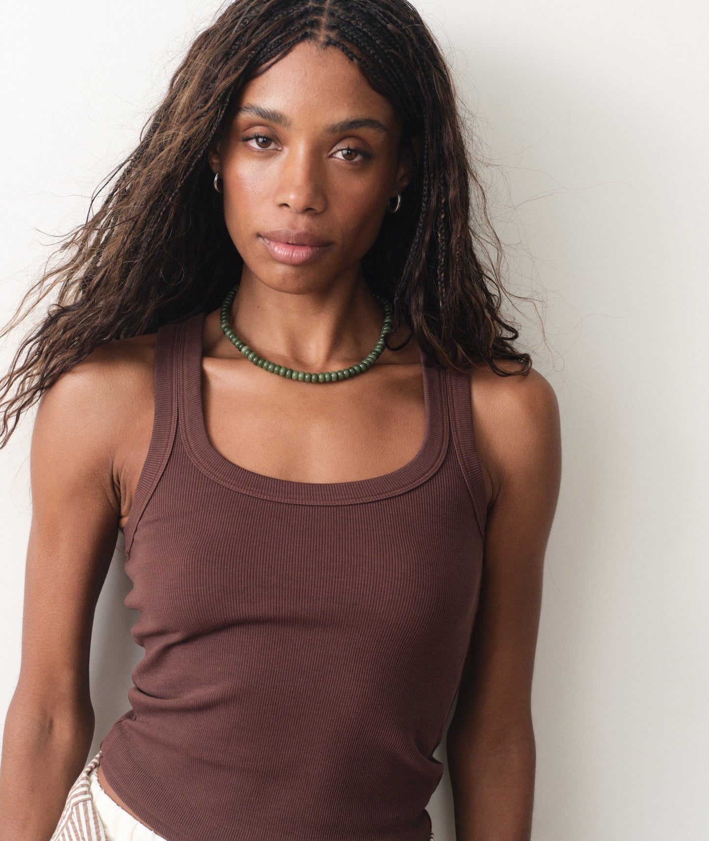 Woman wearing a brown tank top against a plain background