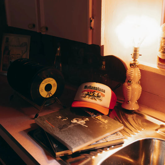 Vinyl record, cap, and book on a kitchen counter with warm lighting.