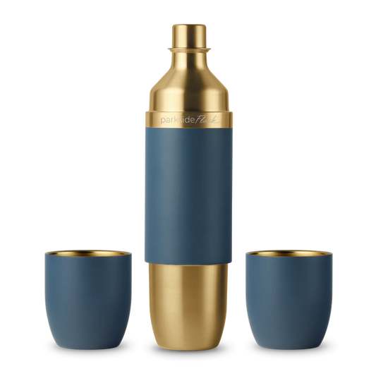 Blue and gold cocktail shaker with two matching cups on a white background