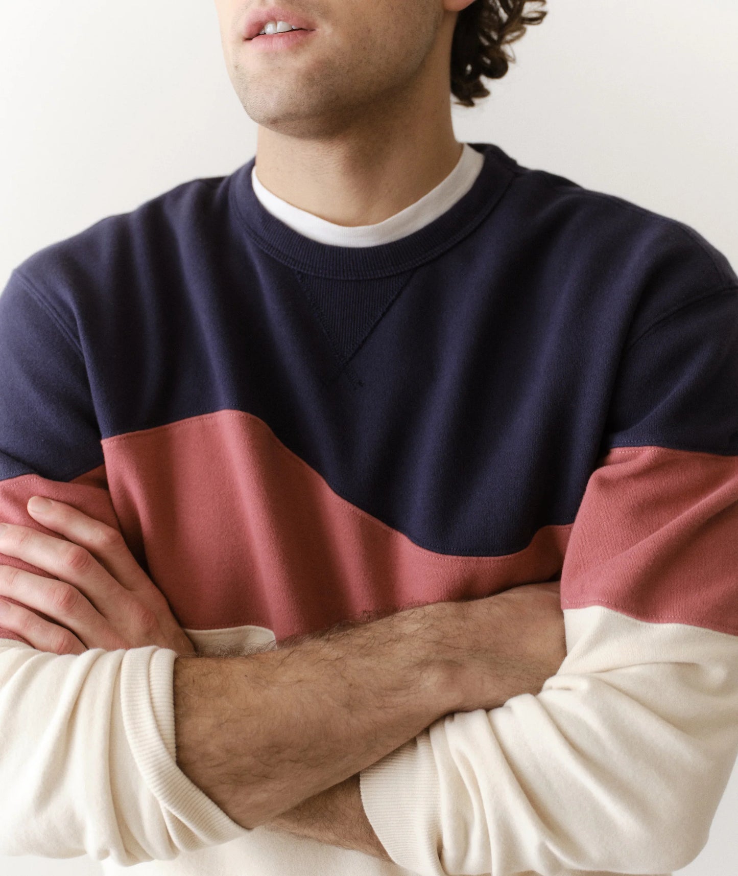Person wearing a navy and red color-blocked sweater with arms crossed.