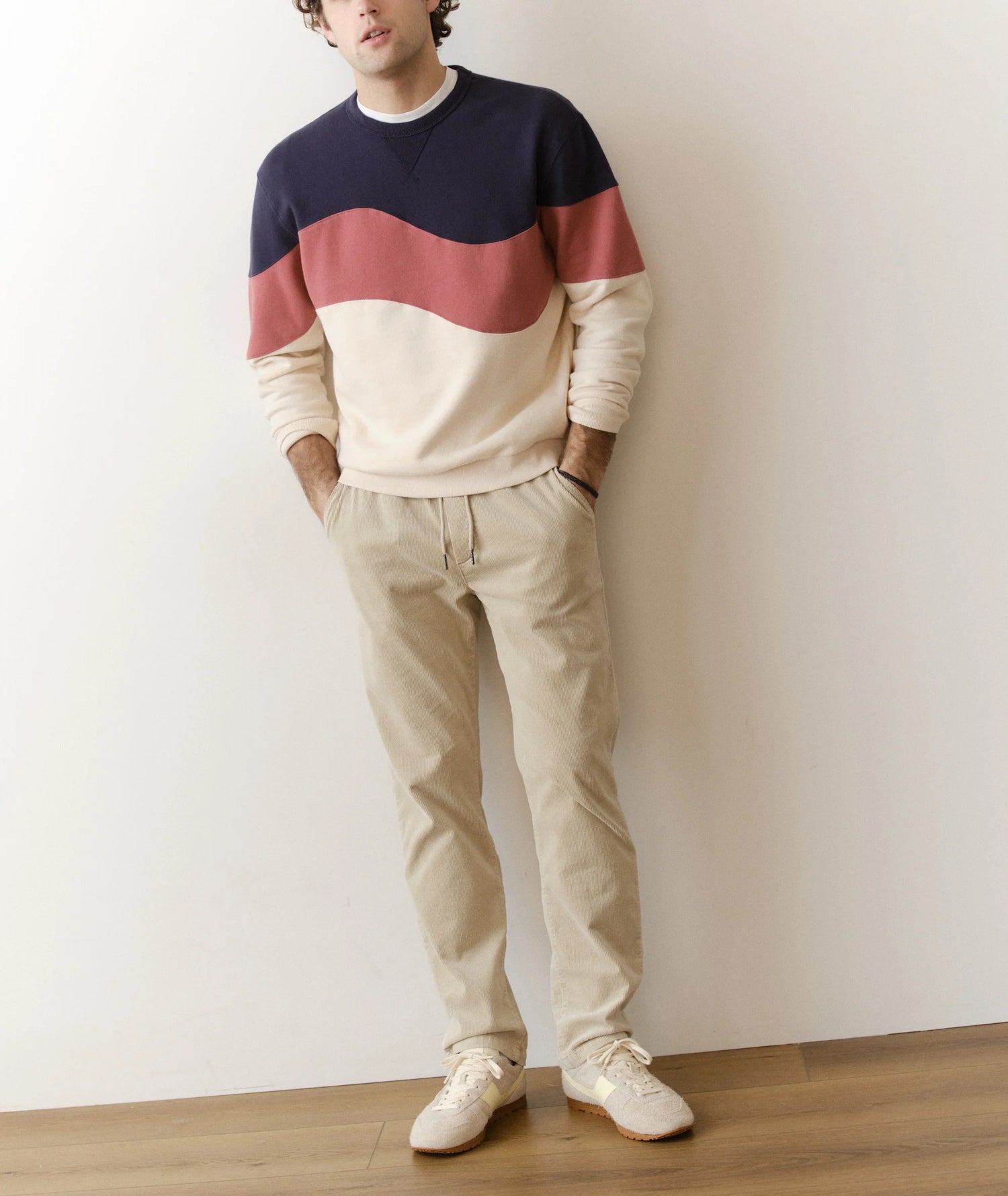 Person wearing a color-blocked sweater and beige pants against a plain background