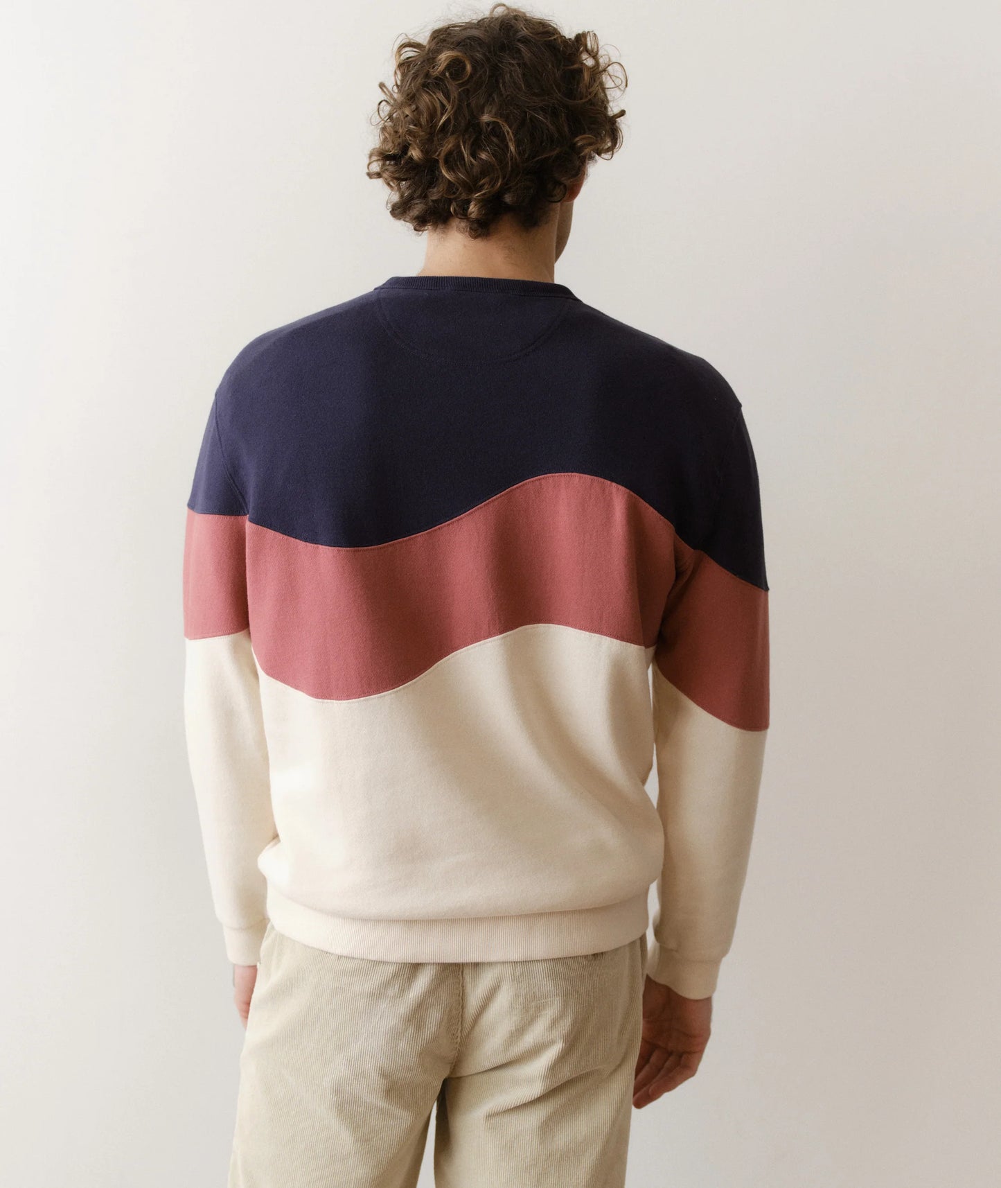 Person wearing a color-blocked sweater with navy, red, and white sections on a plain background