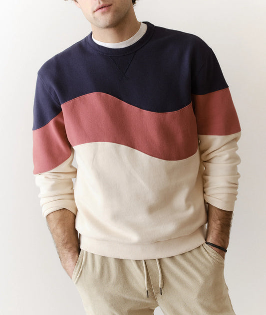 Person wearing a color-blocked sweater with navy, red, and beige sections on a plain background.