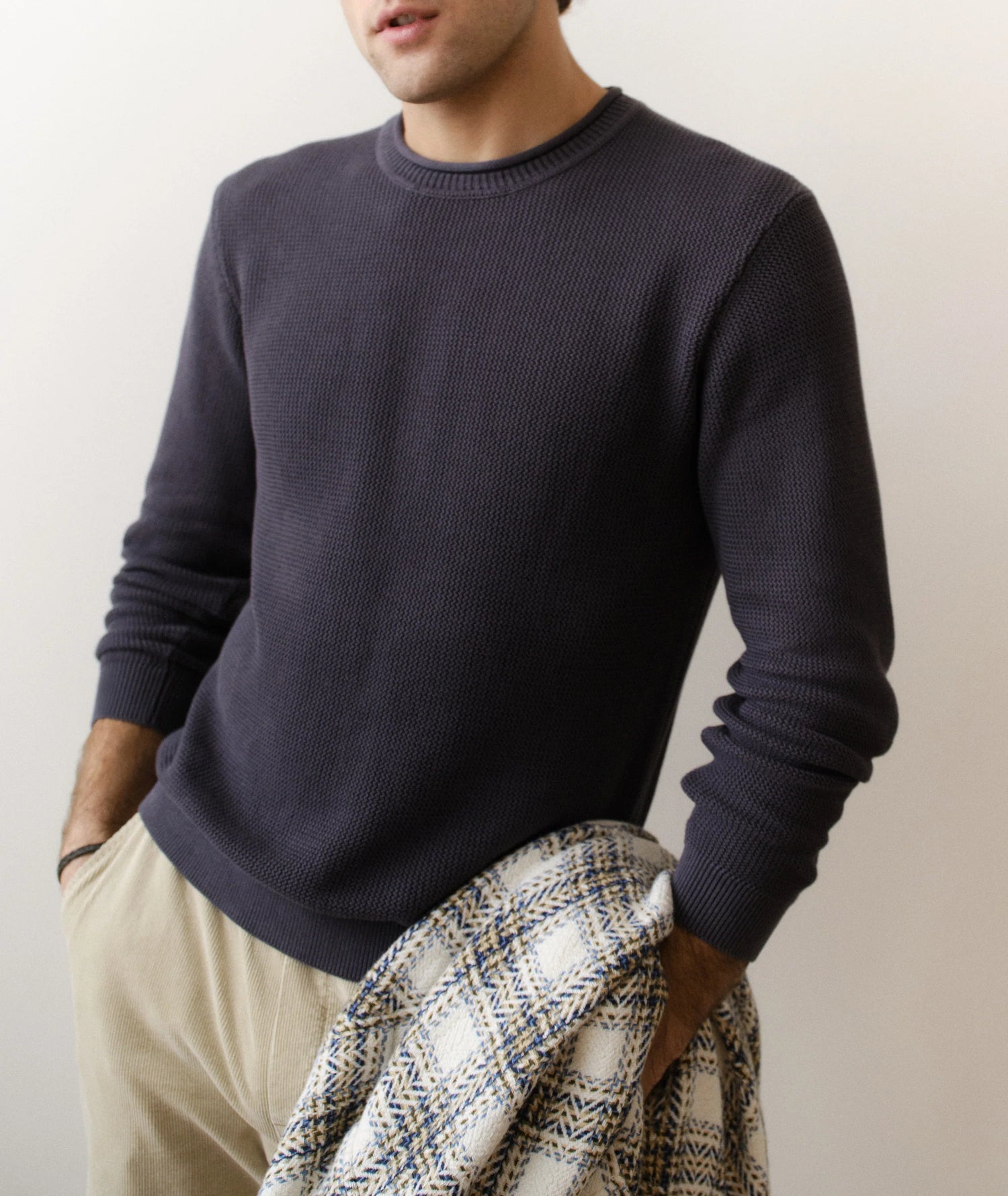 Man wearing a dark blue sweater with a neutral background