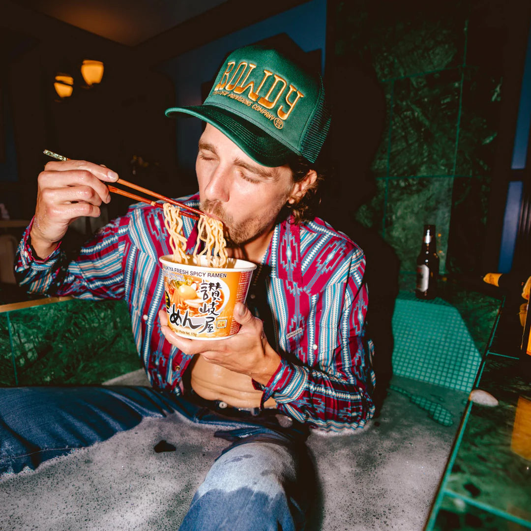 Person eating noodles from a cup with chopsticks in a casual setting
