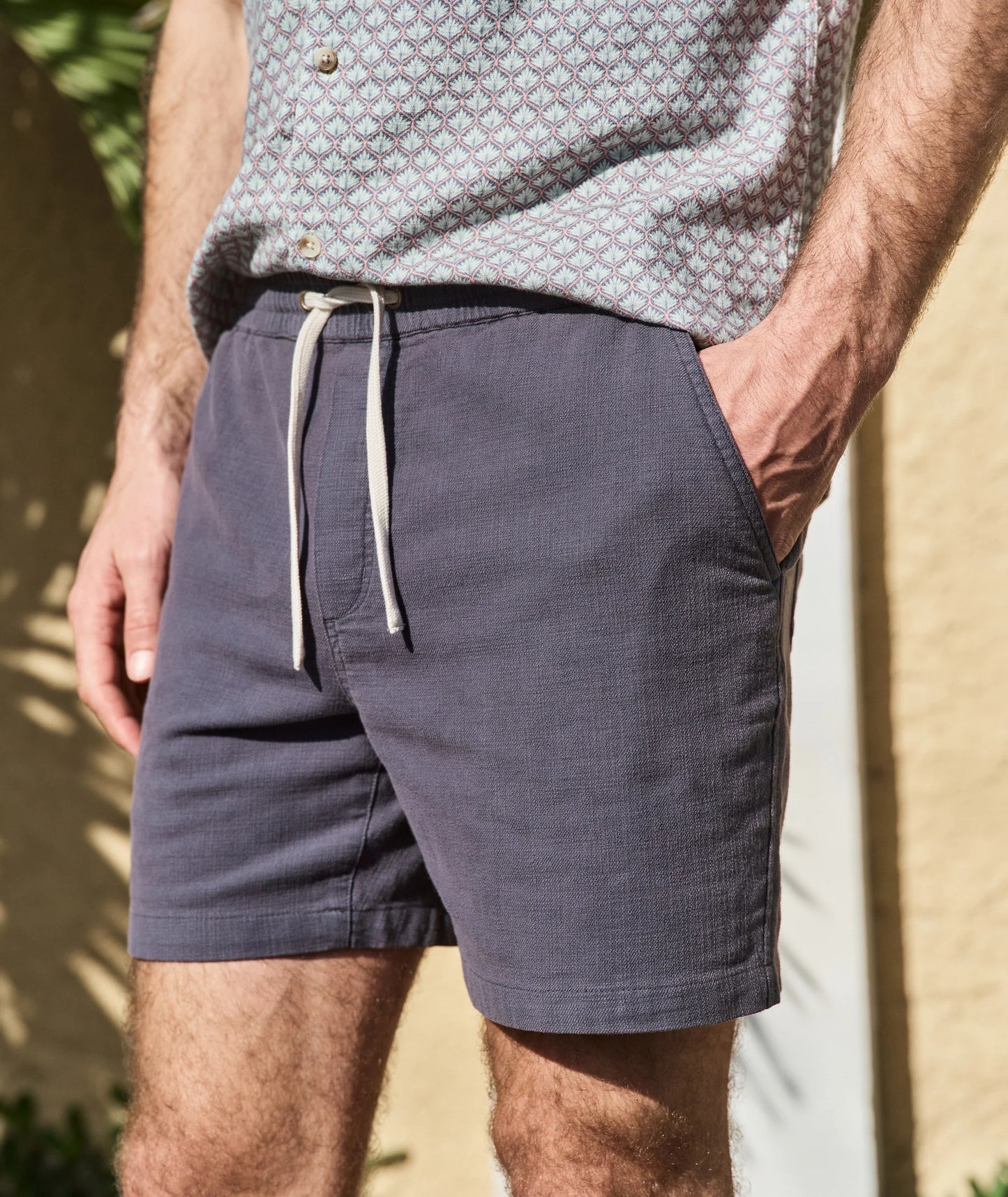 Person wearing navy shorts with a drawstring, standing outdoors.