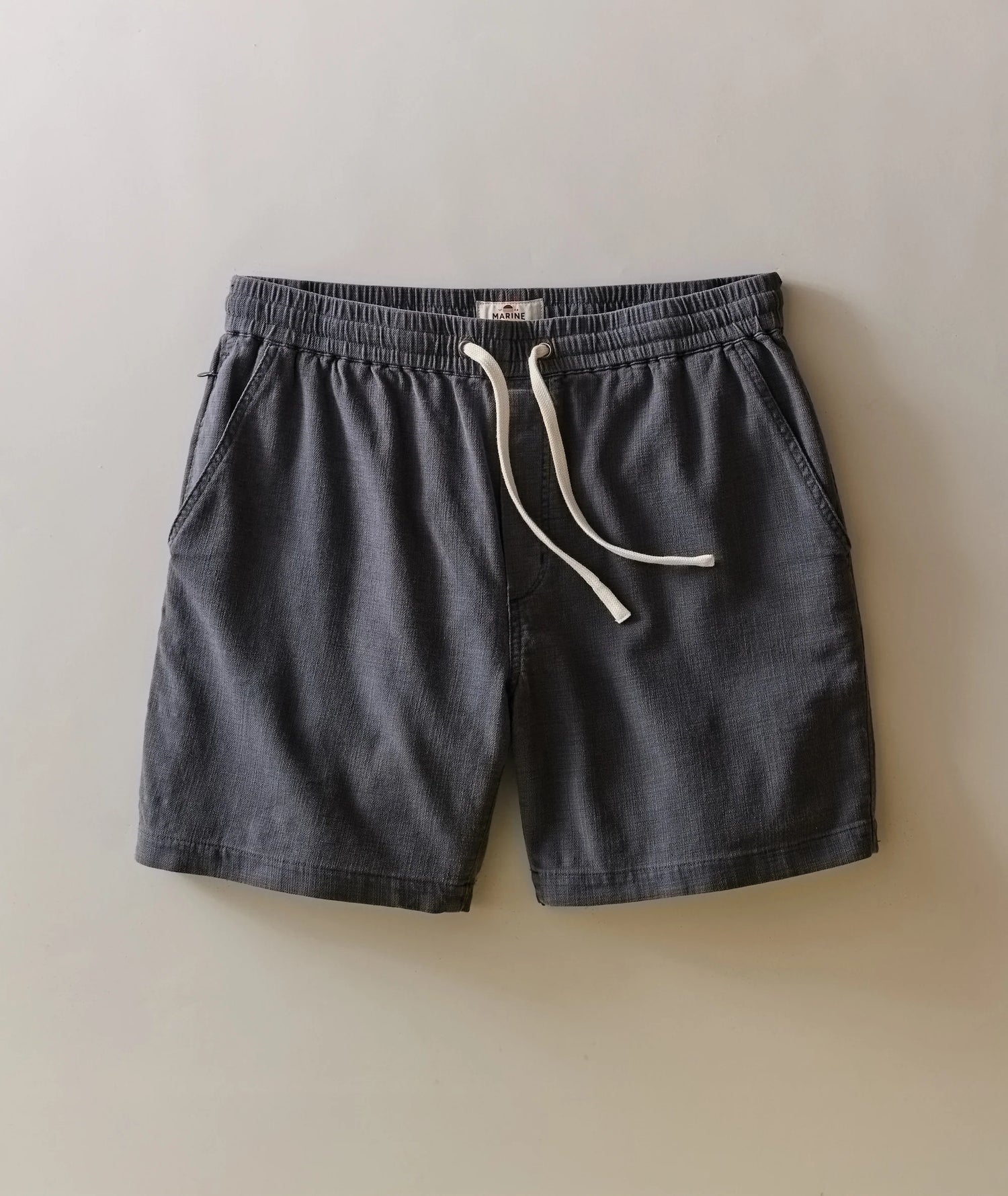 Dark gray shorts with a white drawstring on a beige background