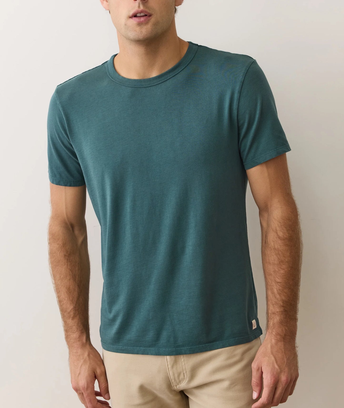 Man wearing a teal t-shirt against a plain background