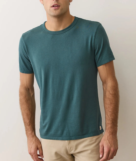 Man wearing a teal t-shirt against a plain background